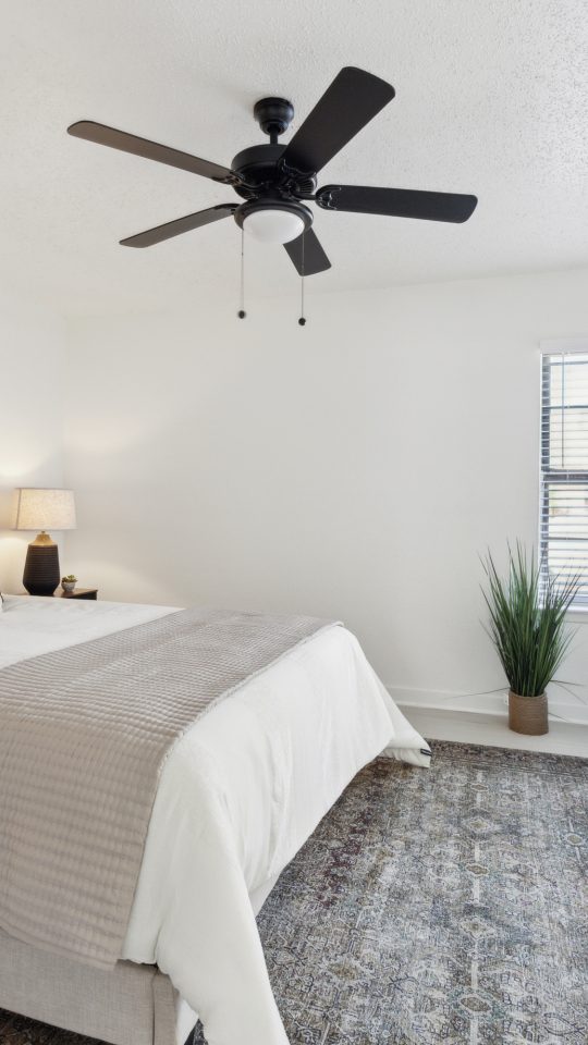 a bedroom with a ceiling fan and white bed at The Brookbend