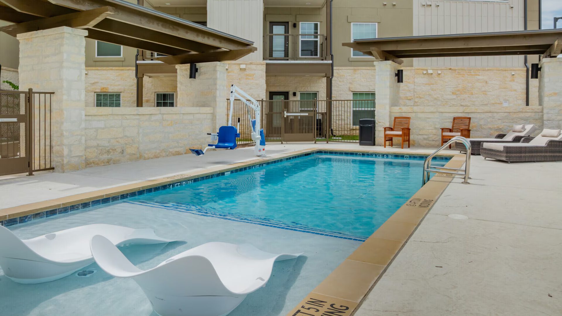 a pool with lounge chairs and a patio area at The Barons Park