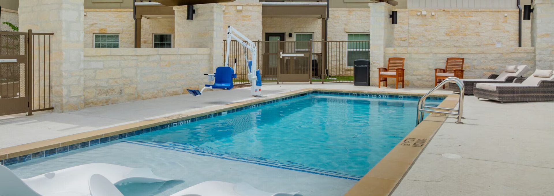 a pool with lounge chairs and a patio area at The Barons Park