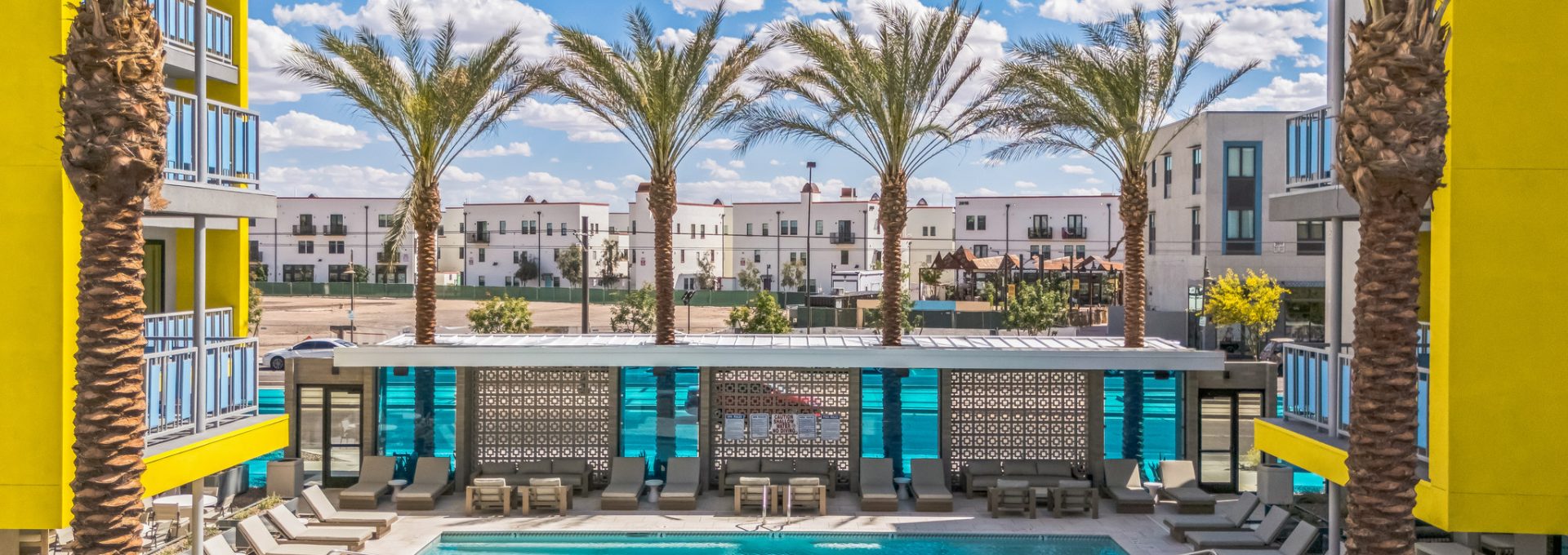 Community pool at Blue Eastline surrounded by palm trees and pool lounge chairs