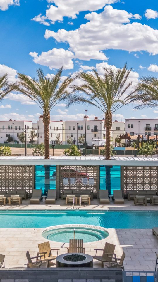 Community pool at Blue Eastline surrounded by palm trees and pool lounge chairs