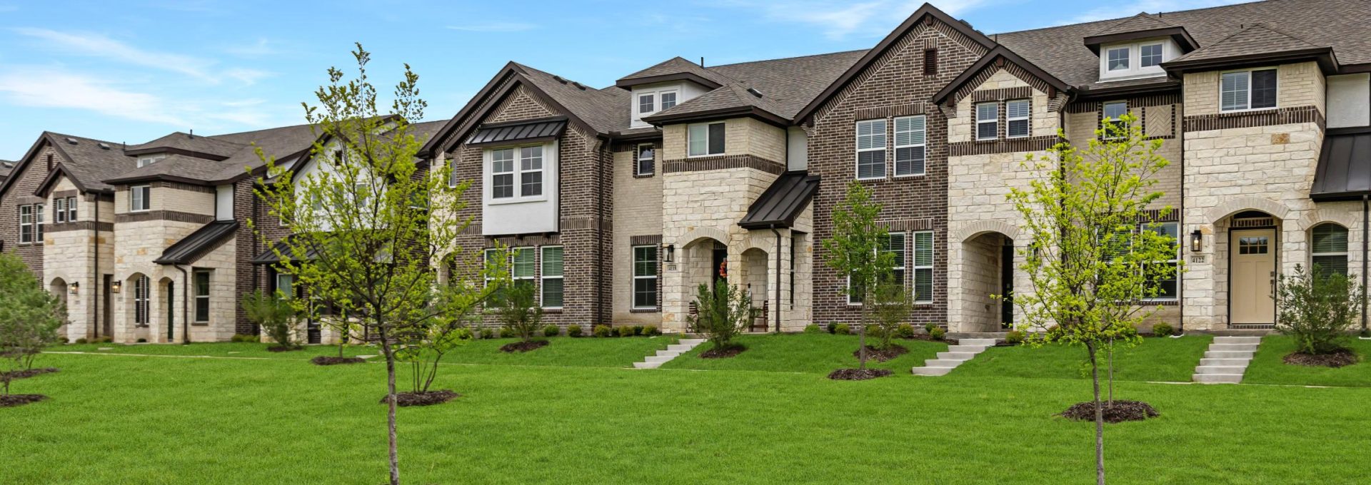 Exterior view of townhomes at The Villas at Bardin's with green grass and trees out front