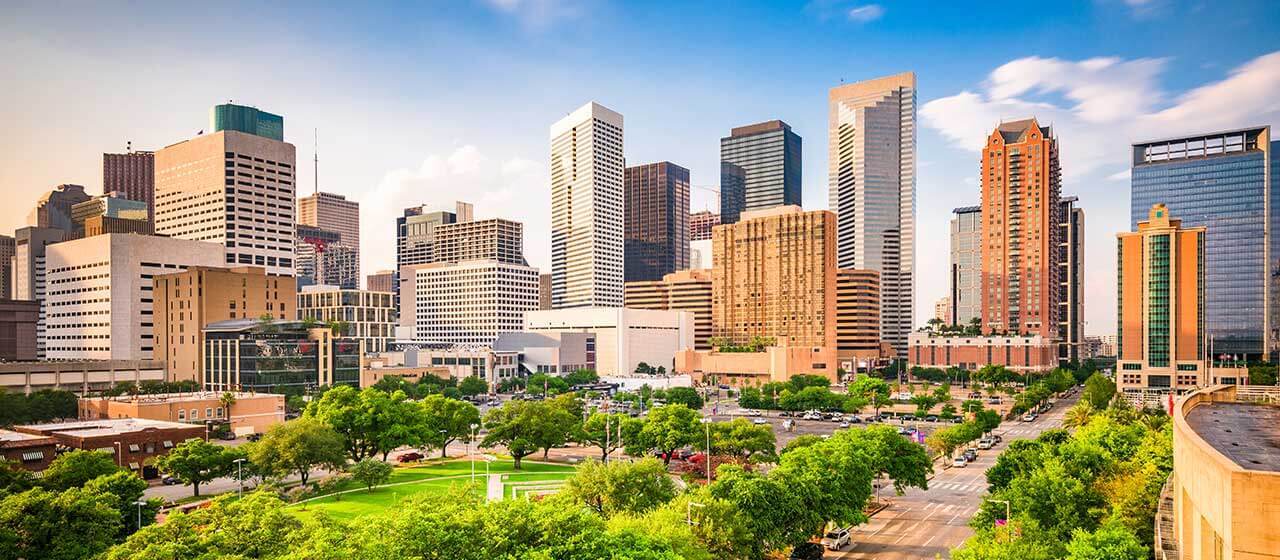a city skyline with tall buildings and green grass at The Studios At Channelview