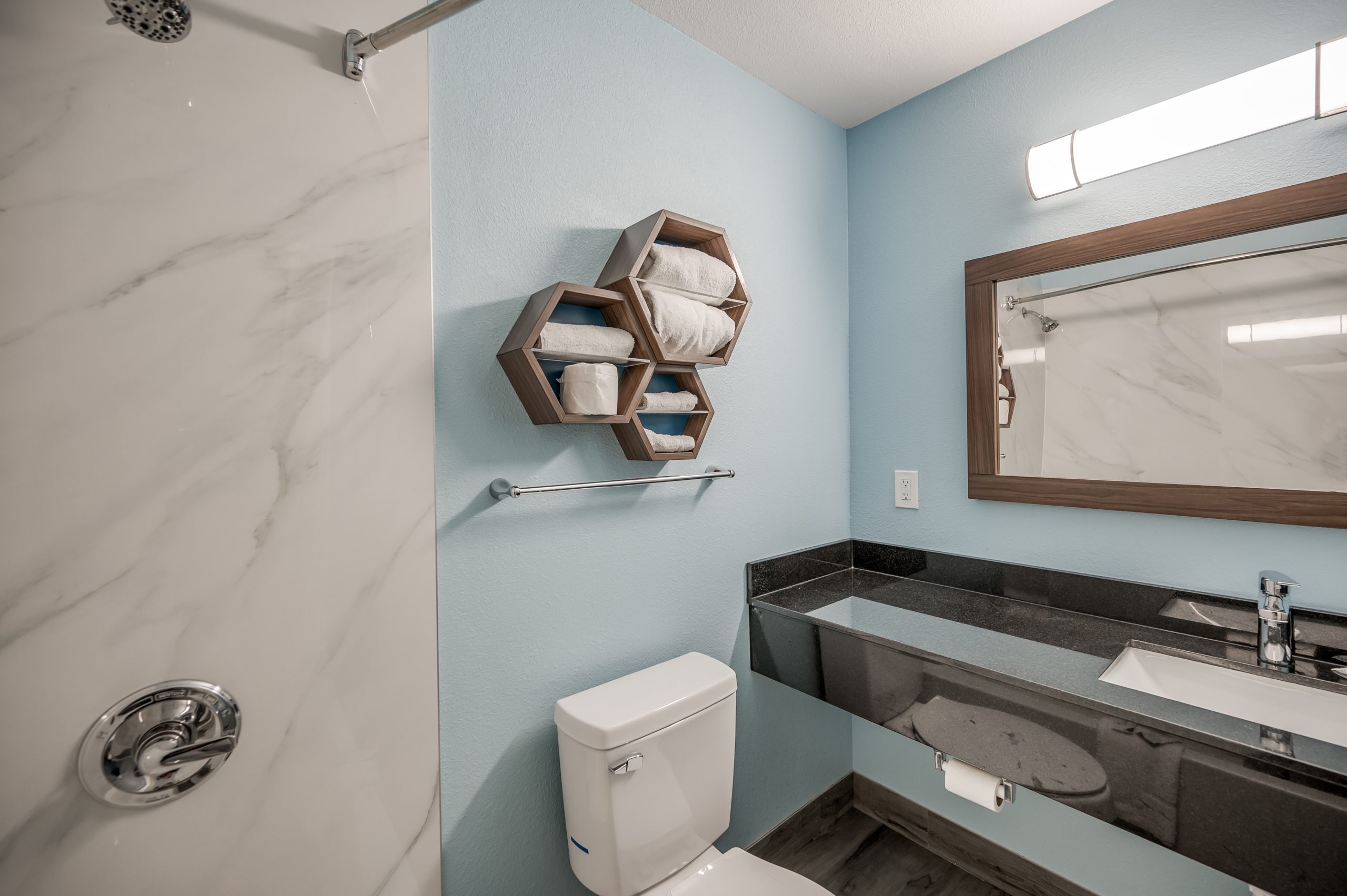 a bathroom with a toilet, sink and mirror at The Studios At Channelview