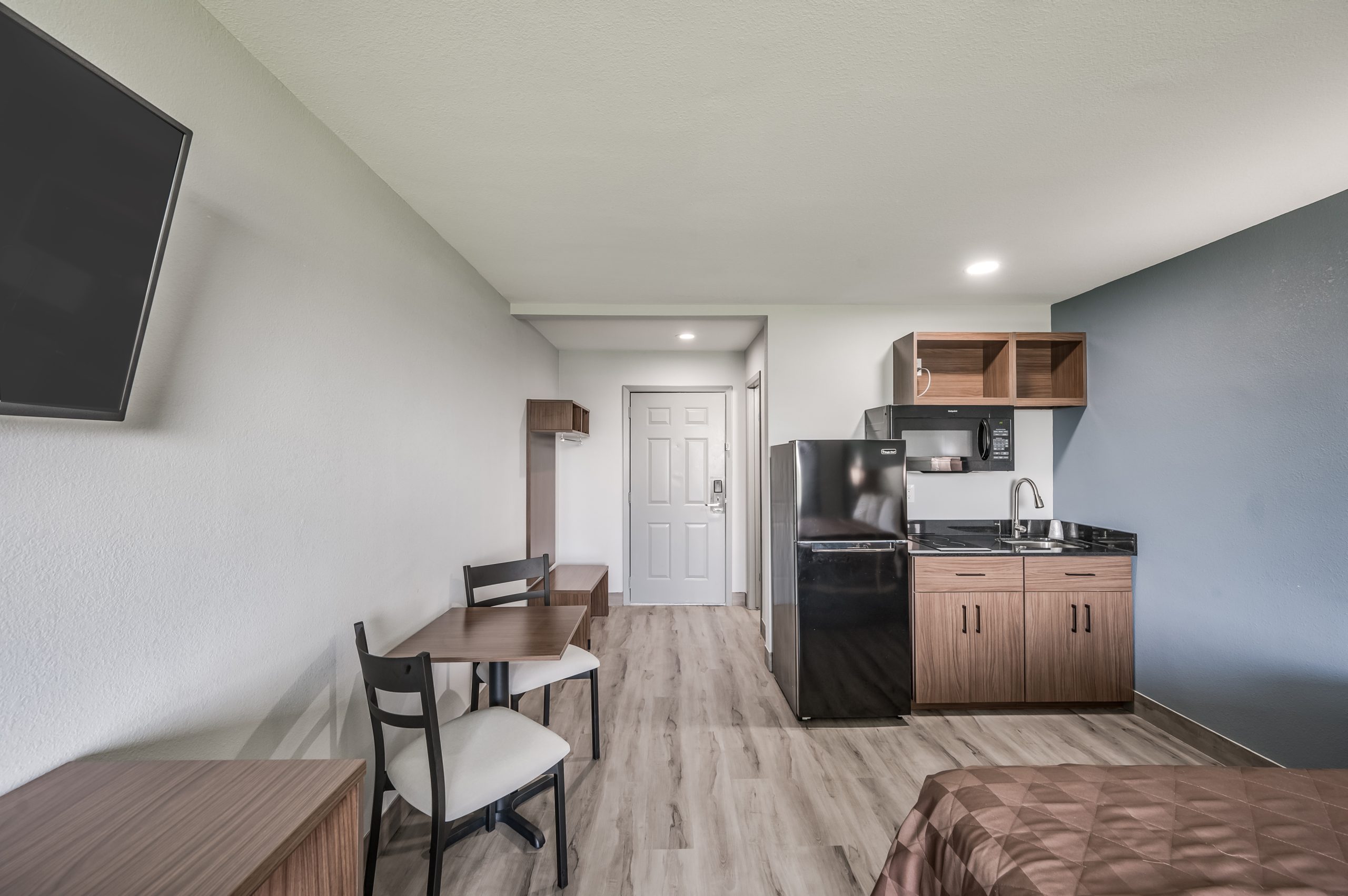 a small kitchen with a microwave, refrigerator and a small table at The Studios At Channelview