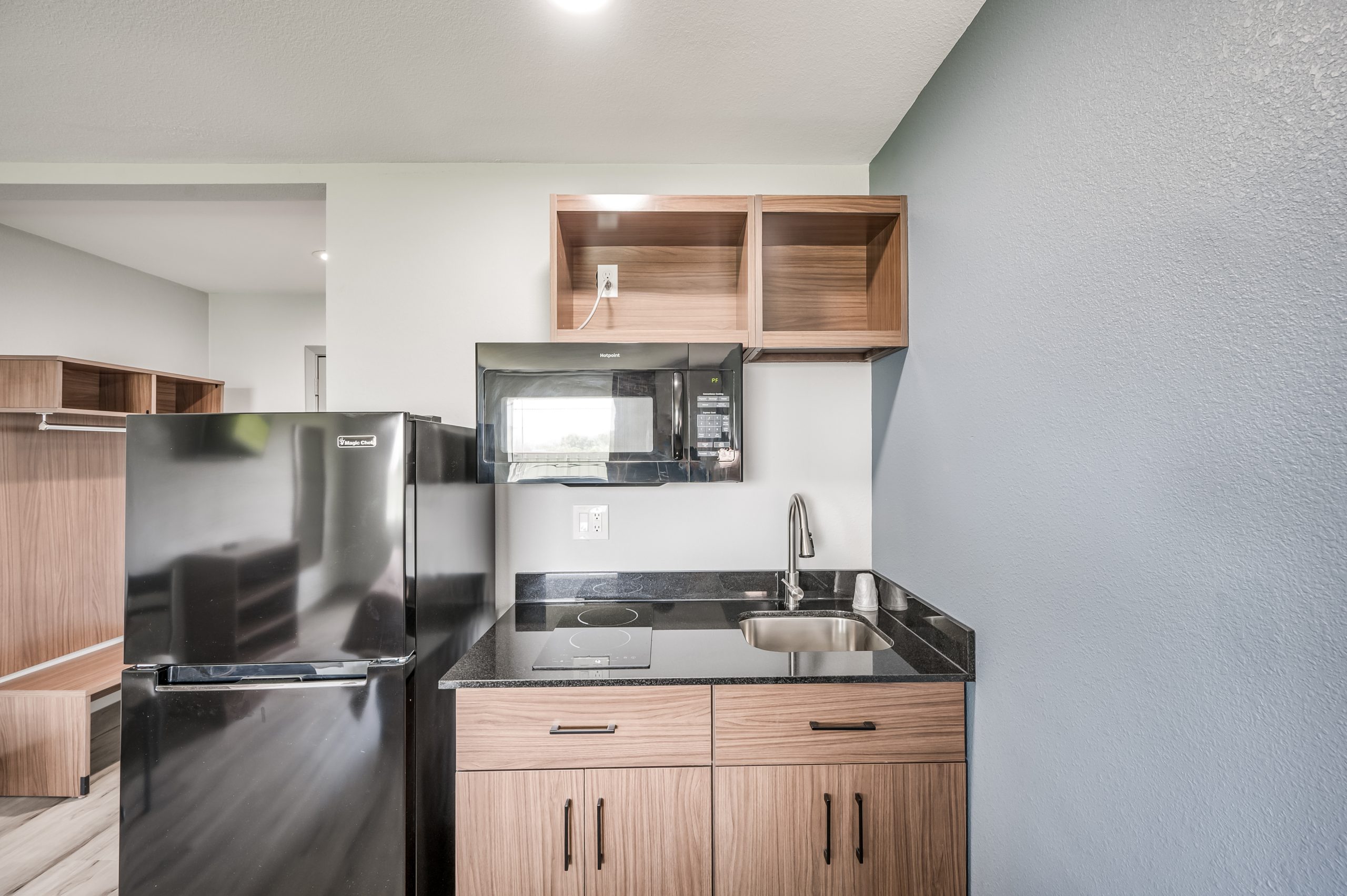 a kitchen with a microwave, refrigerator and sink at The Studios At Channelview