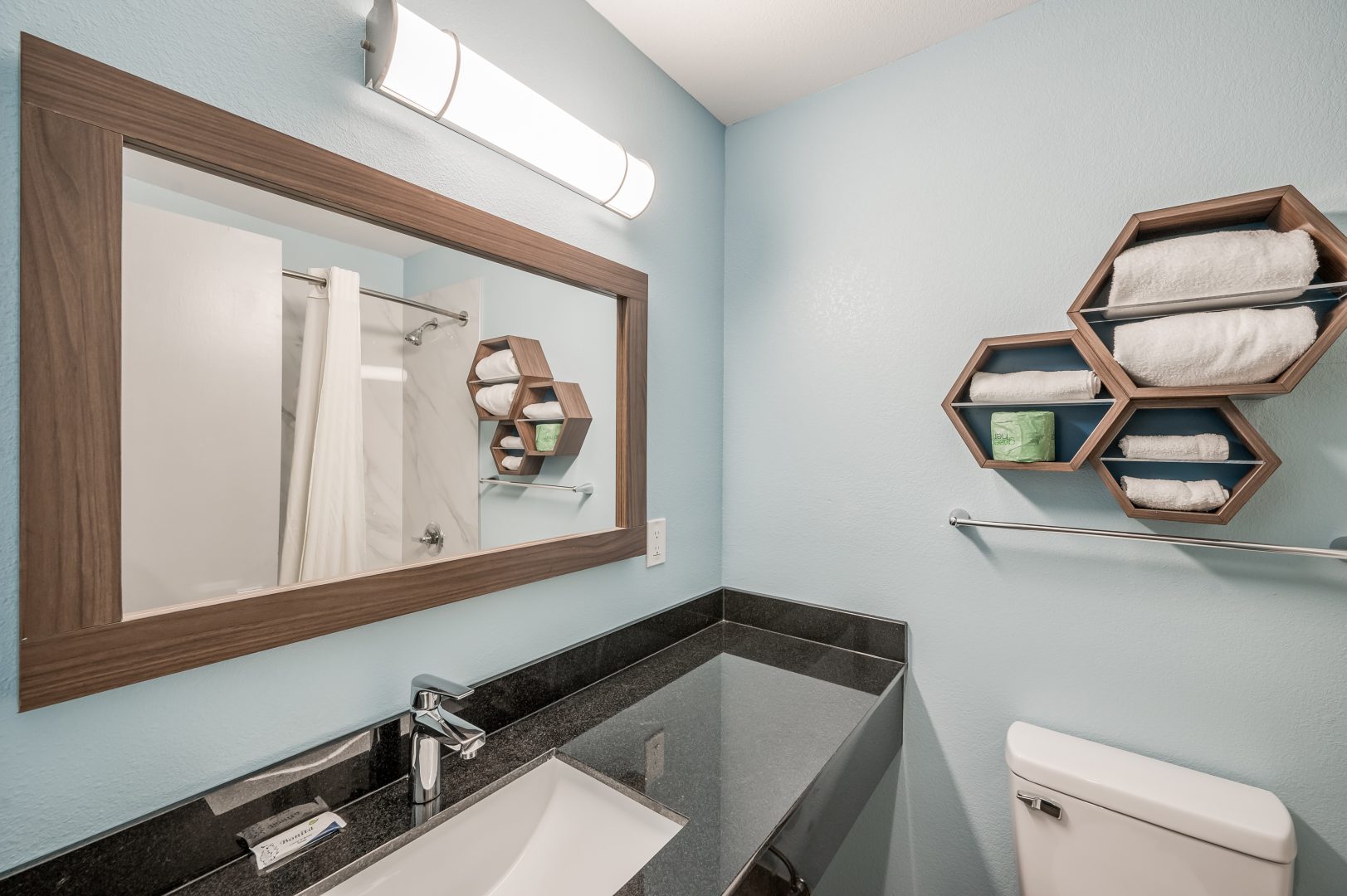 a bathroom with a sink, toilet and mirror at The Studios At Channelview