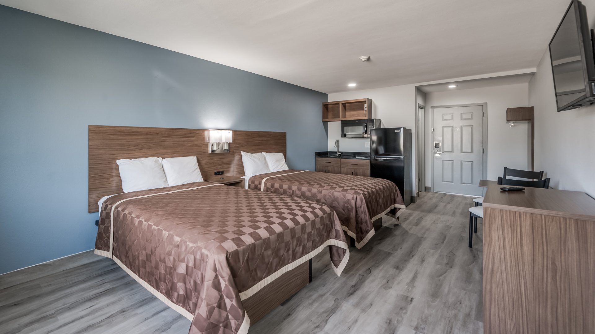 a motel room with two beds and a television at The Studios At Channelview