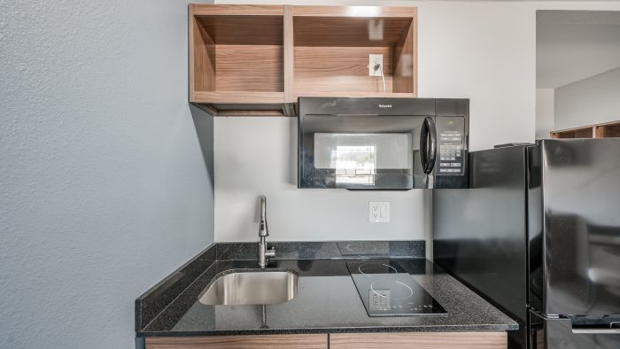 a kitchen with a microwave, sink and refrigerator at The  Studios At Channelview