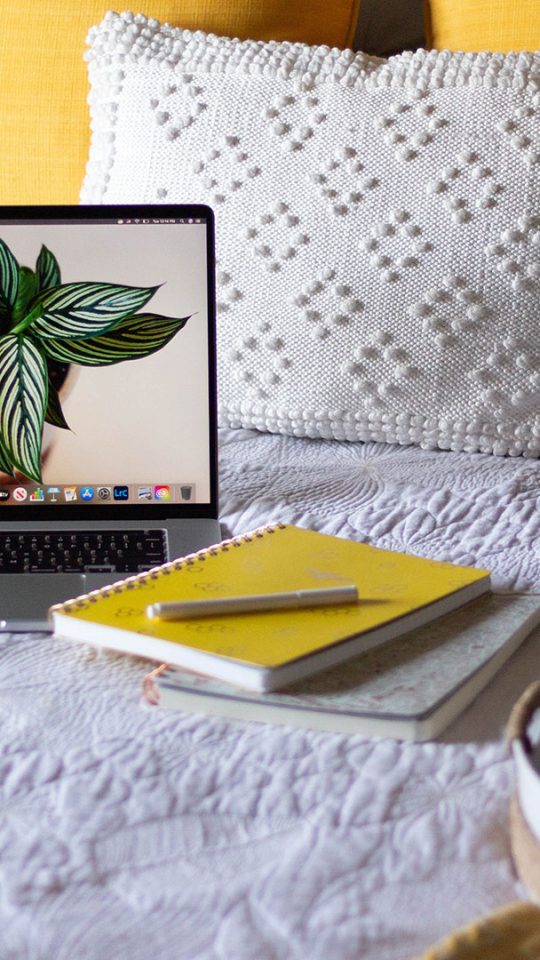 Stock photo of a laptop and journal on a bed