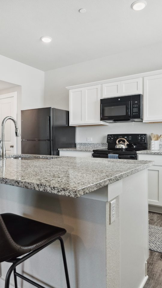 Modern kitchen with granite countertops and stainless steel appliances inside homes at The Powell