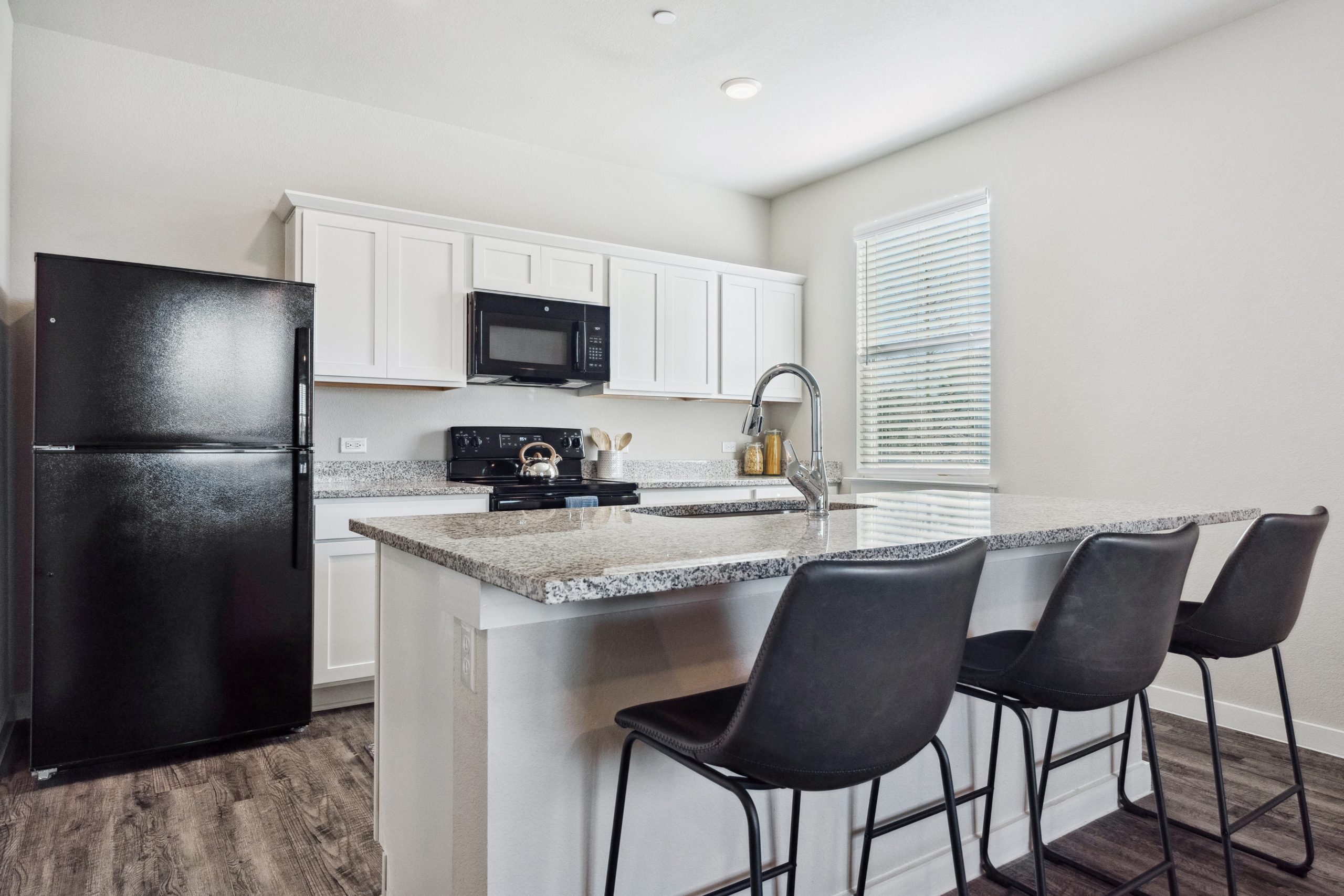 kitchen with black bar stools and white cabinets at The Powell