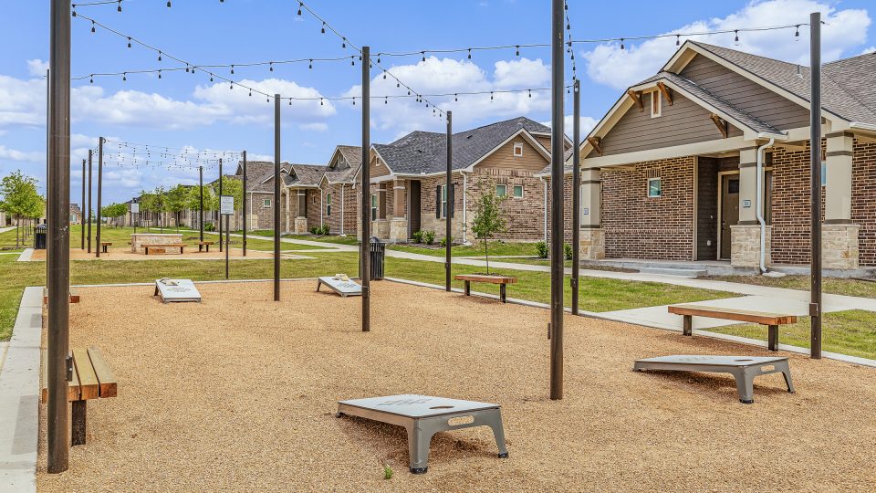 a playground with benches and lights in front of a house at The VLux Stoneridge