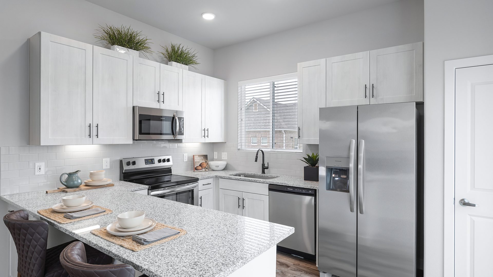 a kitchen with stainless steel appliances and white cabinets at The VLux Stoneridge
