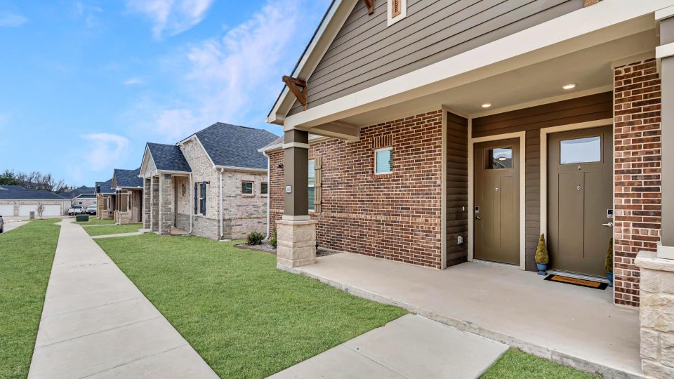 a home with a front porch and grass at The VLux Stoneridge