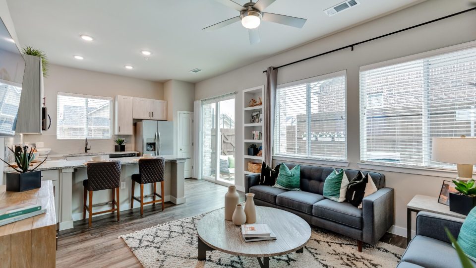 a living room and kitchen area with a ceiling fan at The VLux Stoneridge