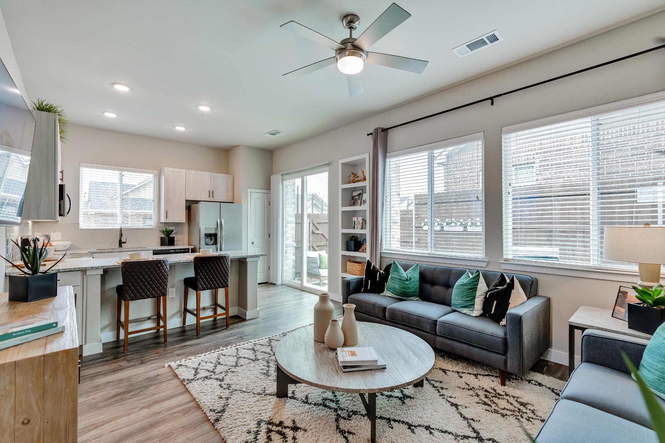 a living room and kitchen area with a ceiling fan at The VLux Stoneridge