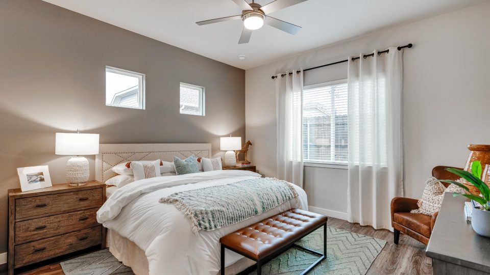 Furnished bedroom with a ceiling fan and hardwood floors inside homes at VLux Stoneridge