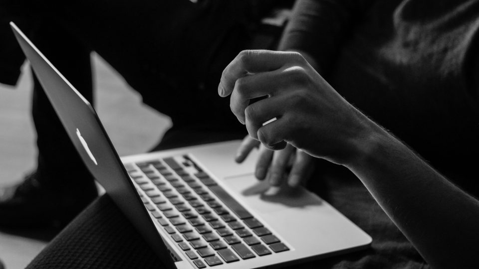 Grayscale photo of person using MacBook