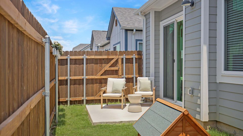 Fenced in backyard with grass and outdoor furniture at VLux Trails