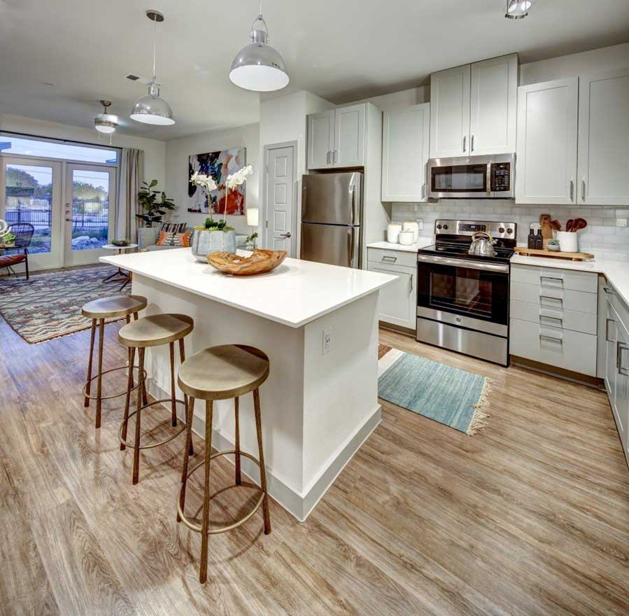 a kitchen with stainless steel appliances and wood floors at The Conley