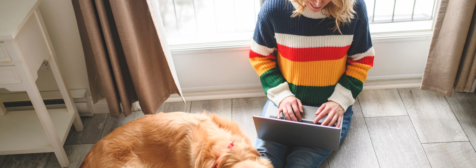 a woman sitting on the floor with a dog and a laptop at The  Conley