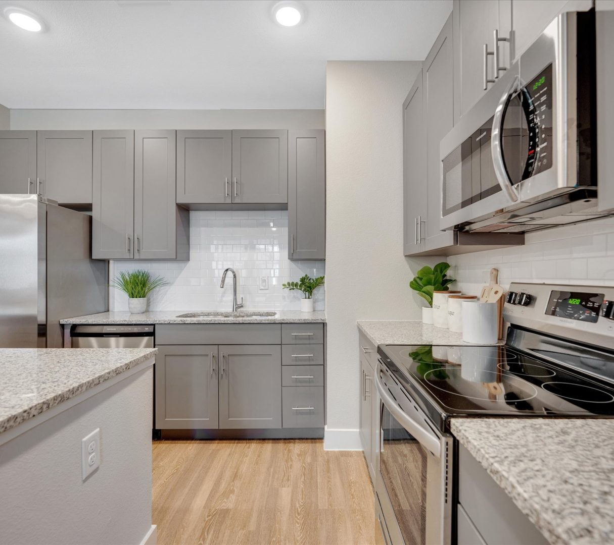 a kitchen with stainless steel appliances and gray cabinets at The Town Arlington