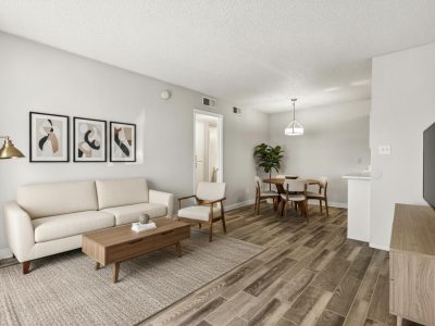 Furnished open living and dining area with a sofa, media console, dining set, and framed art at Country Gables in Glendale, AZ