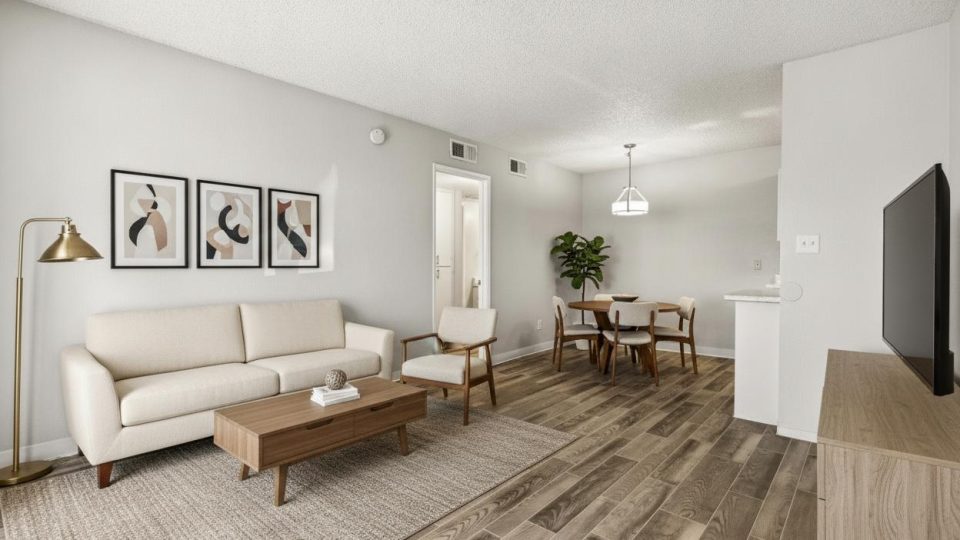 Furnished open living and dining area with a sofa, media console, dining set, and framed art at Country Gables in Glendale, AZ