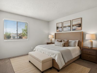 Furnished bedroom with a queen bed, nightstands, bench, and framed art at Country Gables in Glendale, AZ