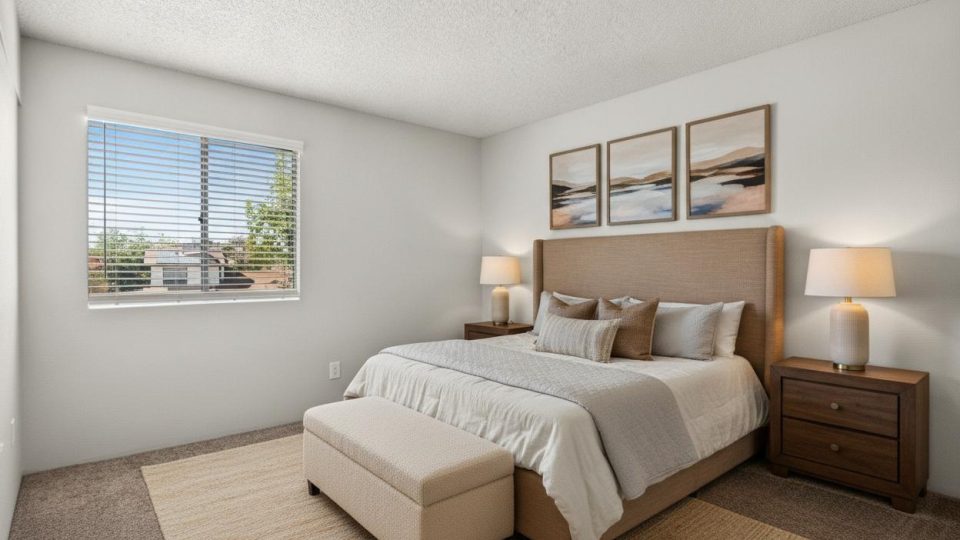 Furnished bedroom with a queen bed, nightstands, bench, and framed art at Country Gables in Glendale, AZ