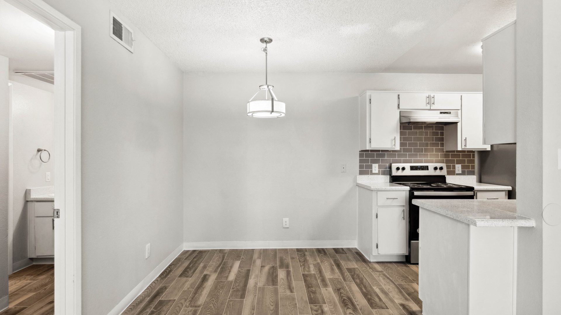 Apartment kitchen with electric range, ample cabinetry, and wood-style flooring at Country Gables