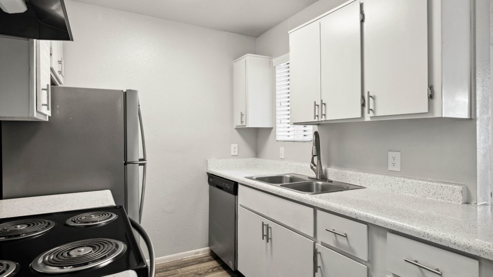 Kitchen featuring a stainless-steel refrigerator, dishwasher, and double basin sink at Country Gables
