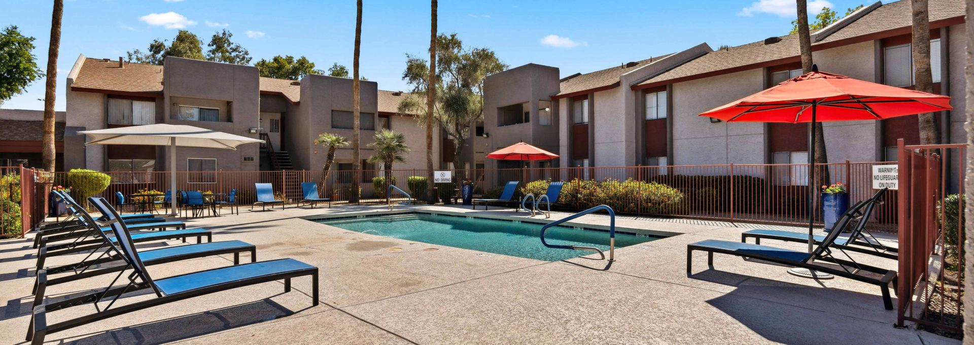 Sparkling community pool and sundeck with lounge chairs and palm trees at Country Gables in Glendale, AZ