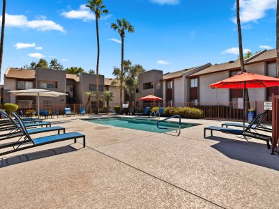 Sparkling community pool and sundeck with lounge chairs and palm trees at Country Gables in Glendale, AZ