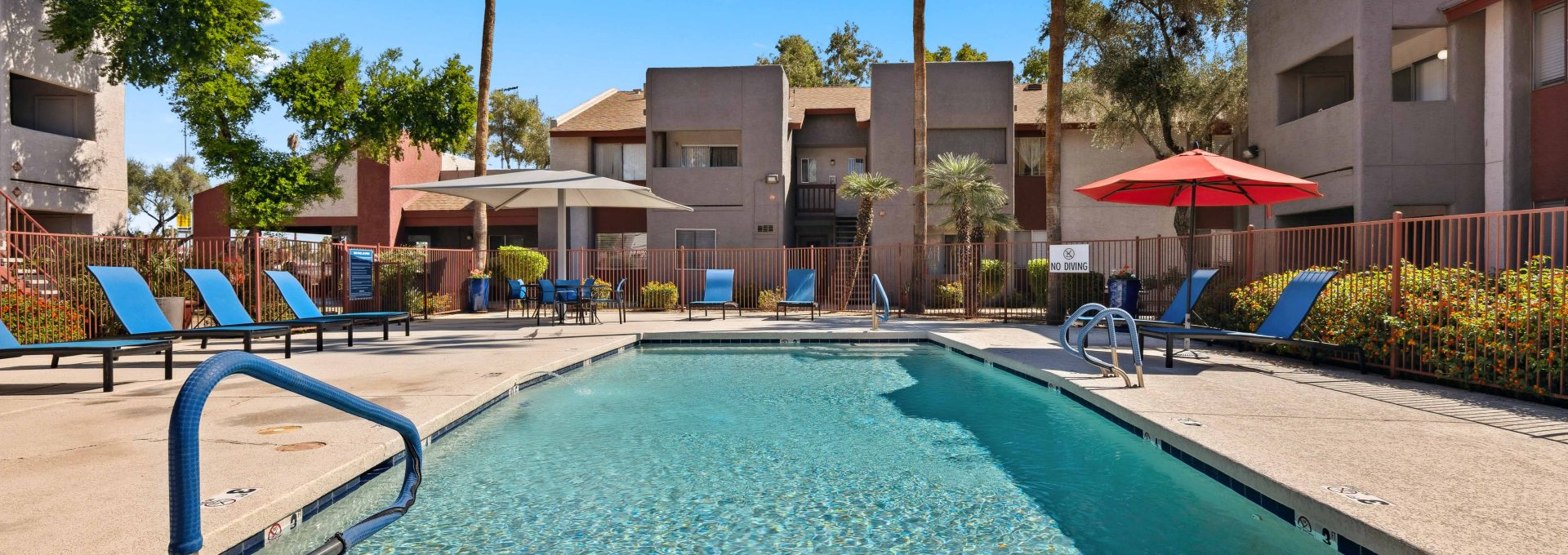 Community swimming pool surrounded by lounge seating and shade umbrellas at Country Gables in Glendale, AZ