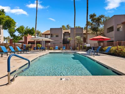 Community swimming pool surrounded by lounge seating and shade umbrellas at Country Gables in Glendale, AZ