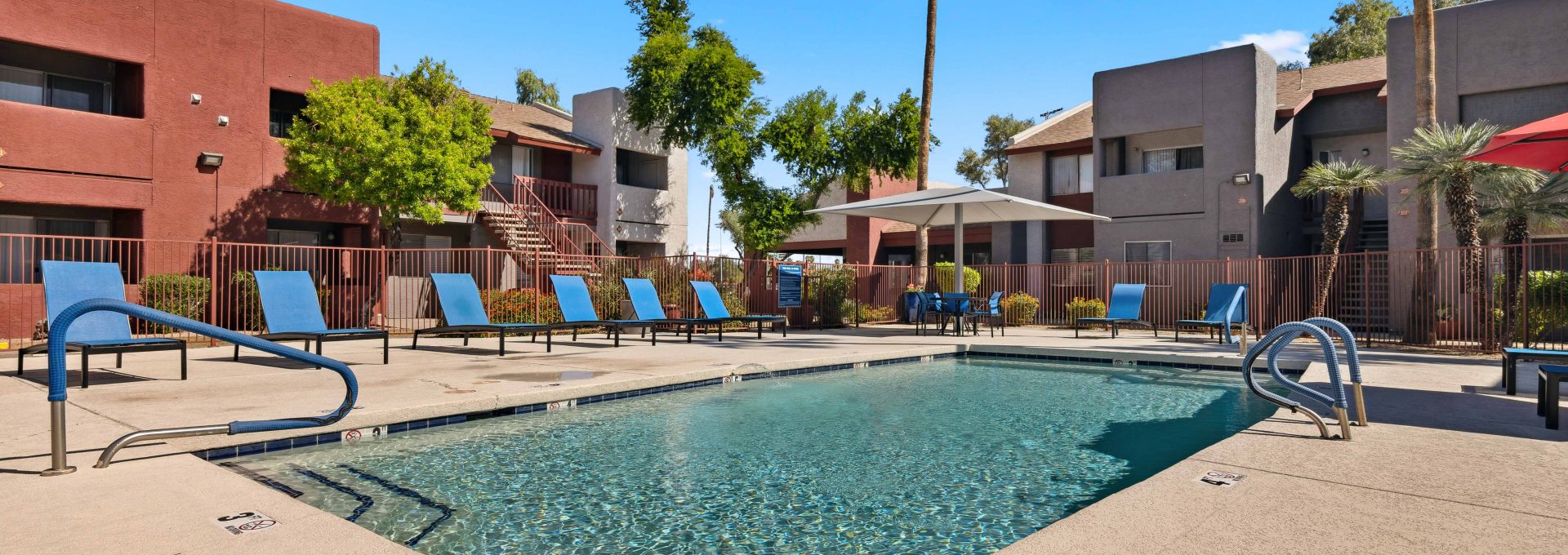 Swimming pool with apartment buildings and mature landscaping in the background at Country Gables