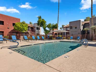 Swimming pool with apartment buildings and mature landscaping in the background at Country Gables