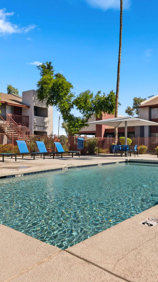 Swimming pool with apartment buildings and mature landscaping in the background at Country Gables