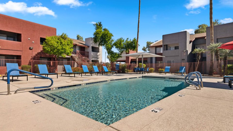 Swimming pool with apartment buildings and mature landscaping in the background at Country Gables