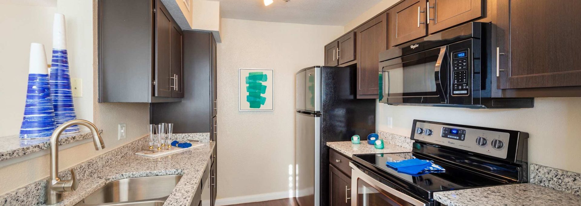 Apartment kitchen with granite countertops, stainless steel appliances and wood flooring at Anchor at South Shore in League City, TX