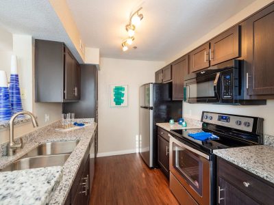 Apartment kitchen with granite countertops, stainless steel appliances and wood flooring at Anchor at South Shore in League City, TX