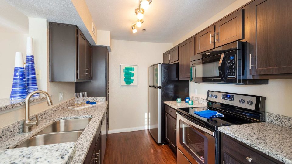 Apartment kitchen with granite countertops, stainless steel appliances and wood flooring at Anchor at South Shore in League City, TX