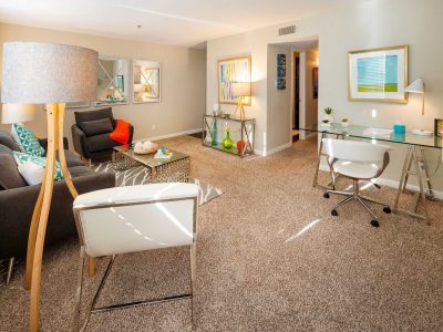 Spacious staged apartment living room with seating area and workspace at Anchor at South Shore in League City, TX