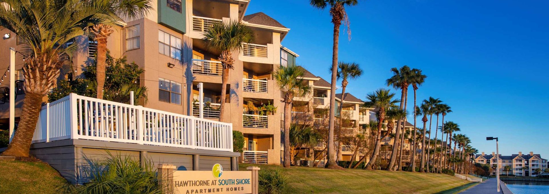 Waterfront apartment building exterior with monument sign, boardwalk and marina at Anchor at South Shore in League City, TX