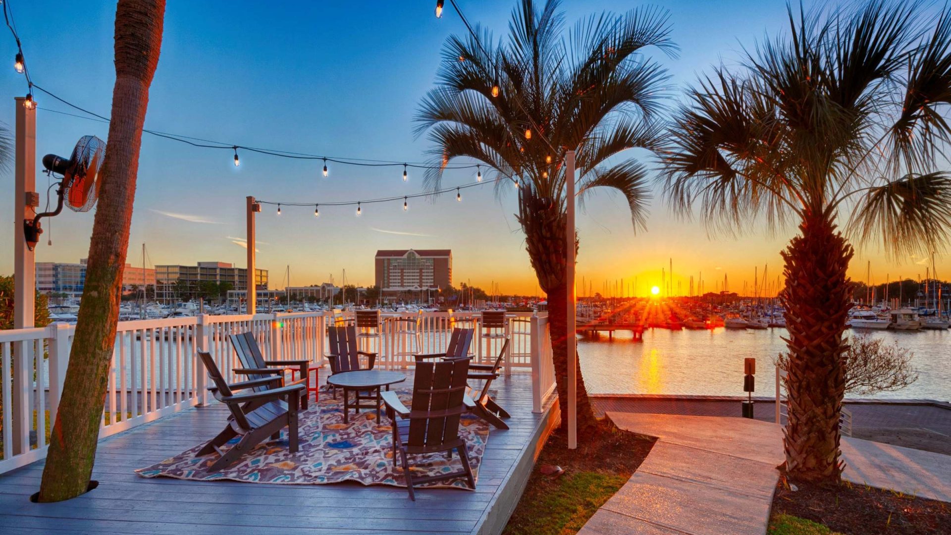Waterfront marina deck with string lights and Adirondack chairs at sunset over South Shore Harbor at Anchor at South Shore in League City, TX