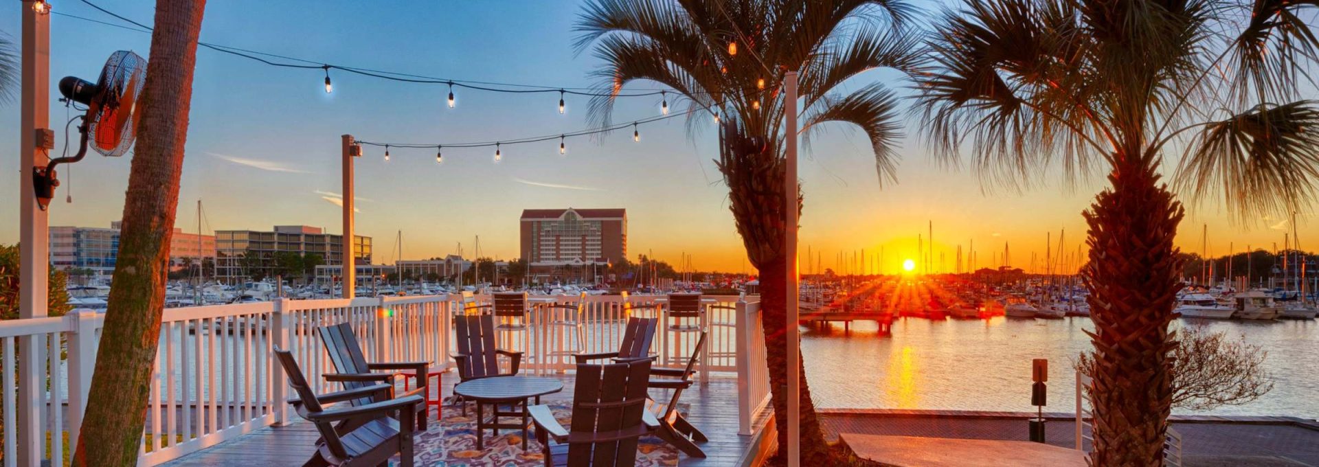 Waterfront marina deck with string lights and Adirondack chairs at sunset over South Shore Harbor at Anchor at South Shore in League City, TX
