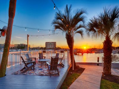 Waterfront marina deck with string lights and Adirondack chairs at sunset over South Shore Harbor at Anchor at South Shore in League City, TX