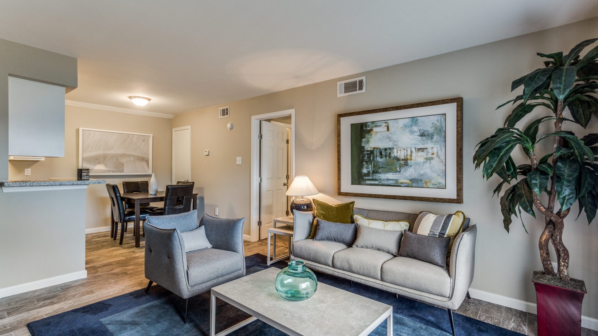 Sunlit staged living room with modern furnishings and wood-style flooring at Clear Creek Landing in Houston, TX